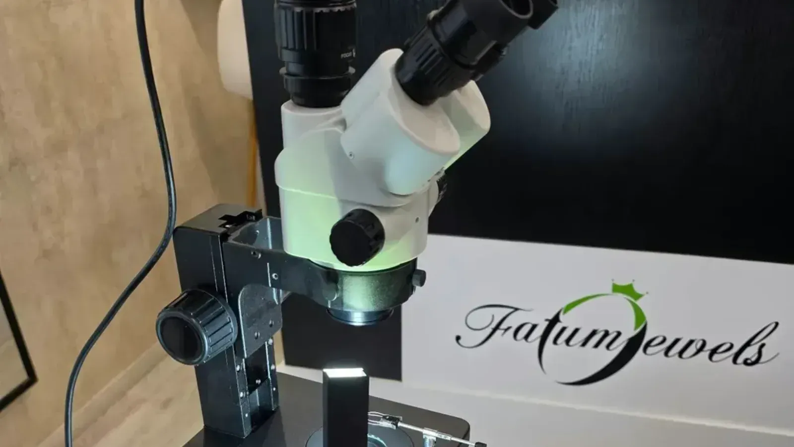 Optika OPTIGEM-20 gemmológiai sztereomikroszkóp a Fatumjewels vizsgálóasztalán, háttérben a Fatumjewels logó